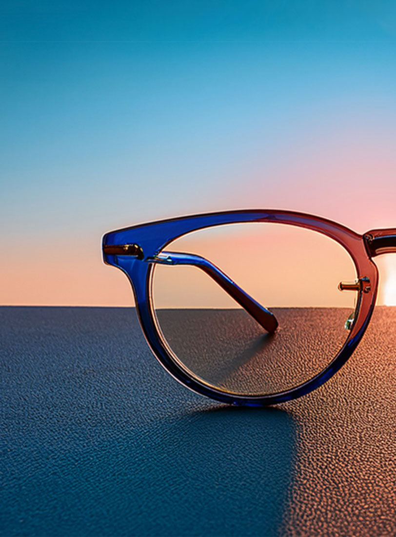Blue-framed glasses on a textured surface with a gradient sky background